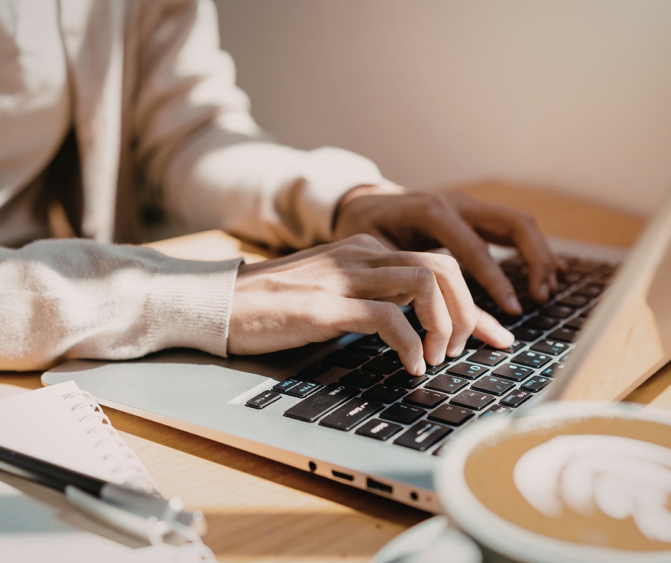 Woman typing on a laptop while researching or scheduling a therapy session