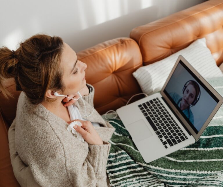 Woman attending an online therapy session from home on a laptop Image Title: