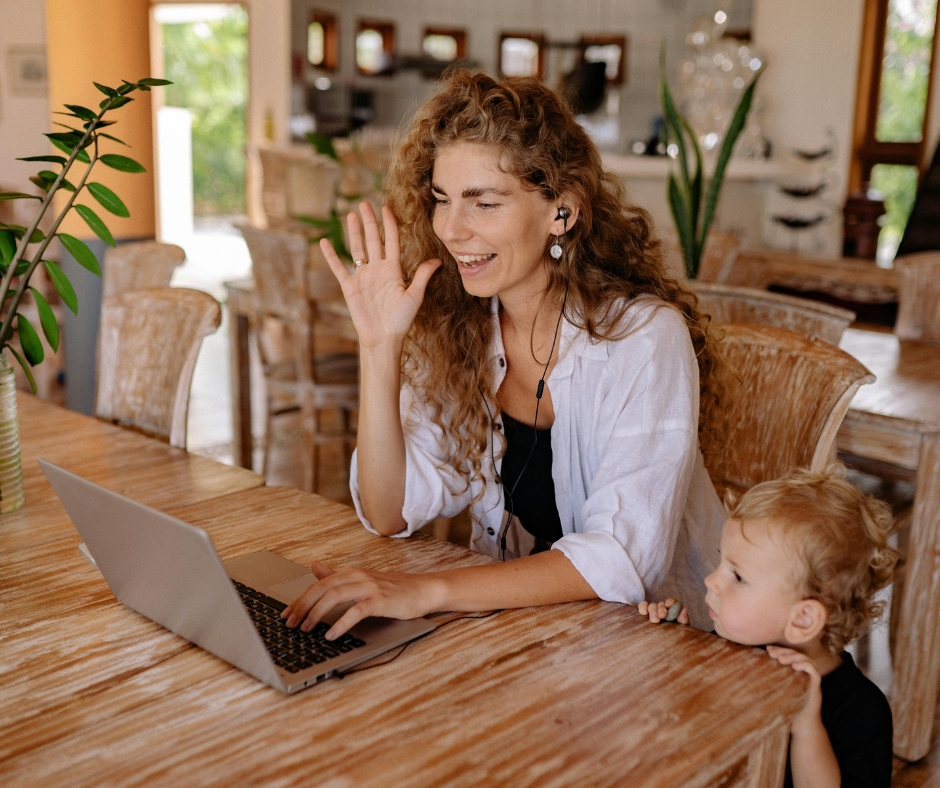 Woman attending an online therapy session while her child plays in the background