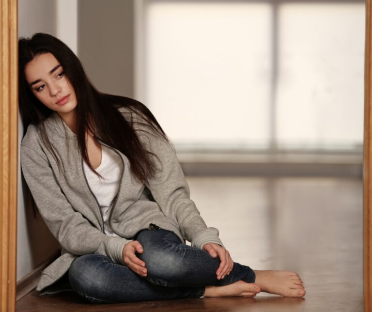 Sad woman sitting alone looking overwhelmed and emotionally exhausted