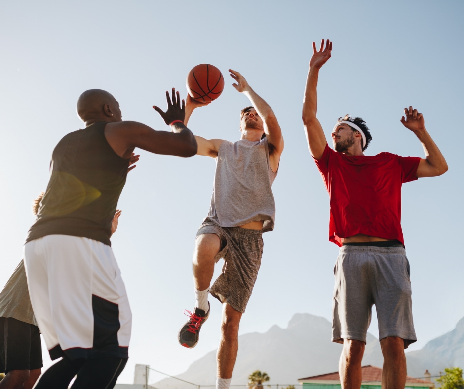 Men playing basketball together on an outdoor court