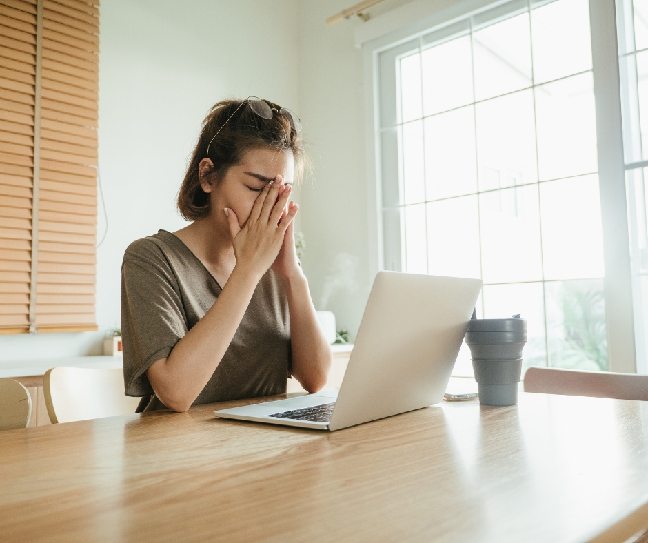 Tired woman working on a laptop while looking overwhelmed and exhausted