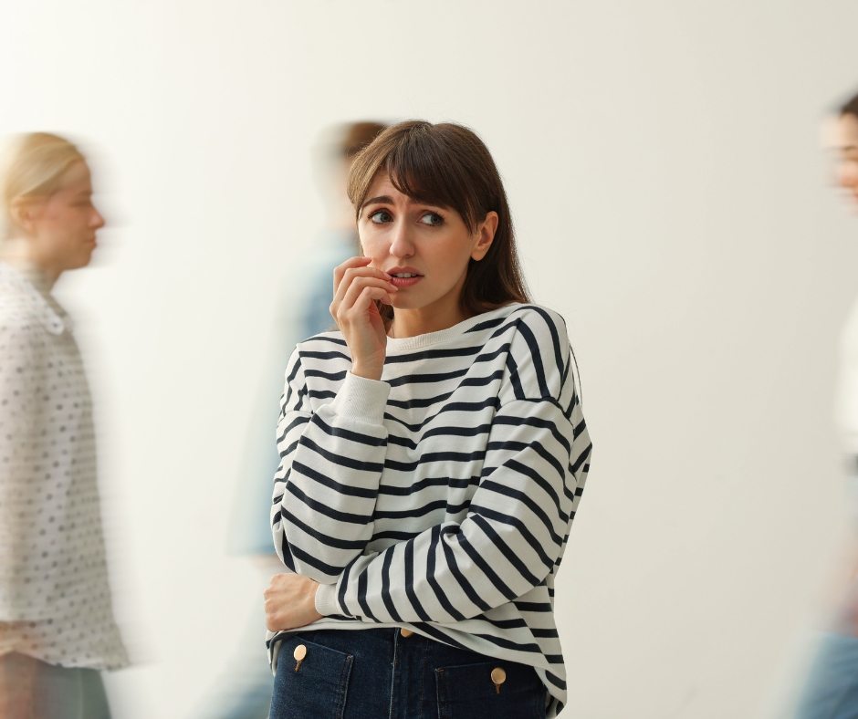 Woman experiencing social anxiety in a crowded public setting while looking overwhelmed and uncomfortable