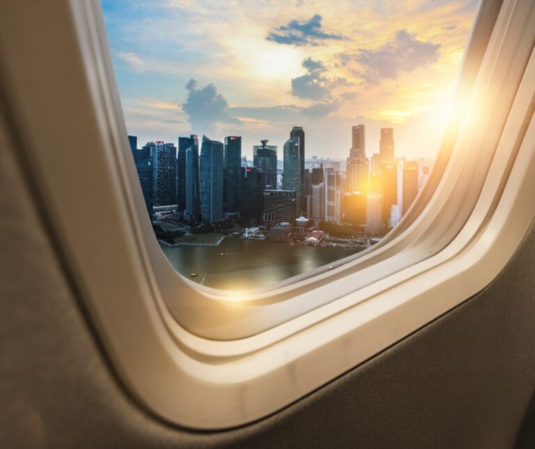 Traveler looking out an airplane window during a flight, reflecting on the journey ahead
